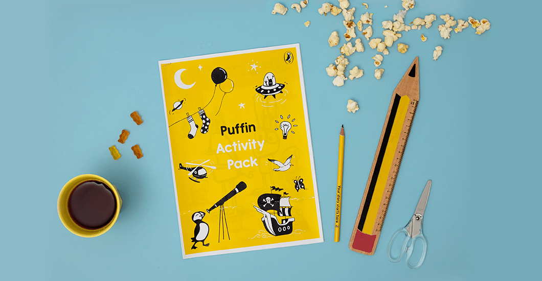 A photo of the printable Puffin activity pack on a light blue background surrounded by some popcorn, a cup of tea, a pencil, ruler and scissors