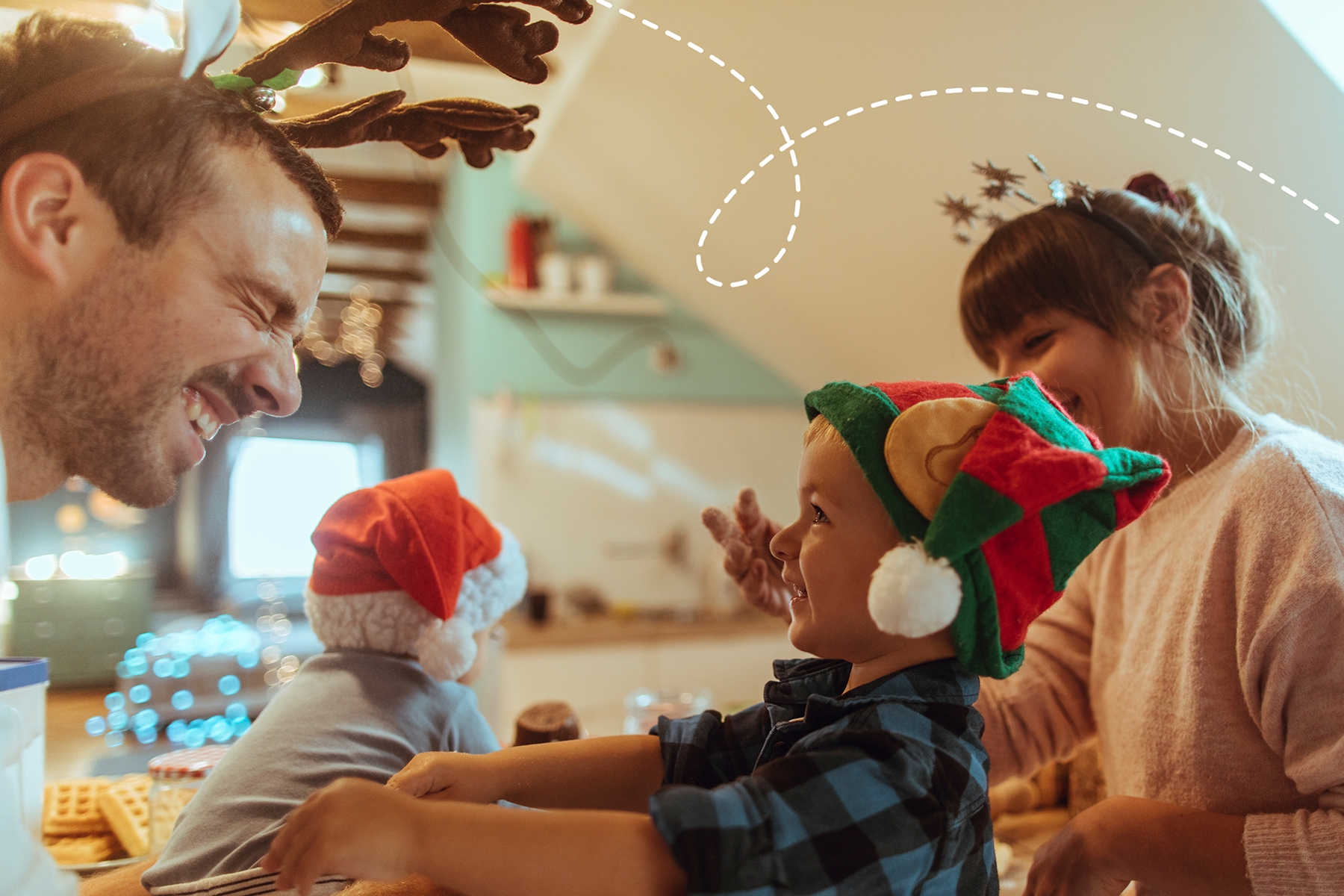 A photo of a dad making a funny face at his toddler son whilst wearing festive antlers